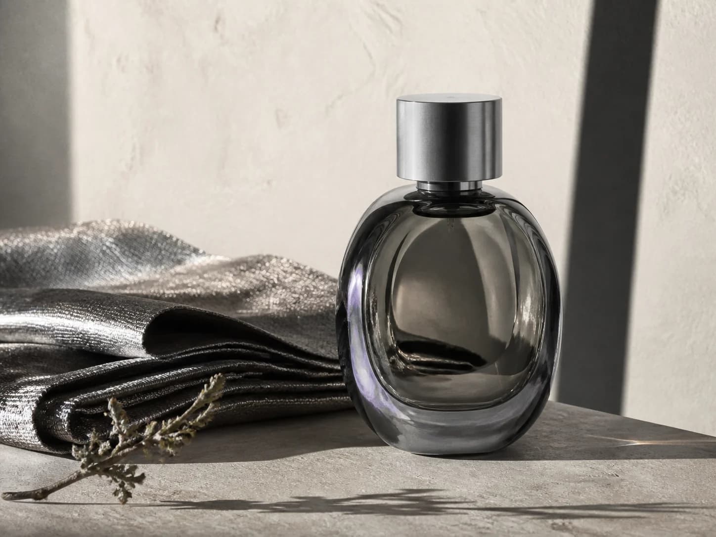 A fragrance bottle in a silver-gray product still life.
